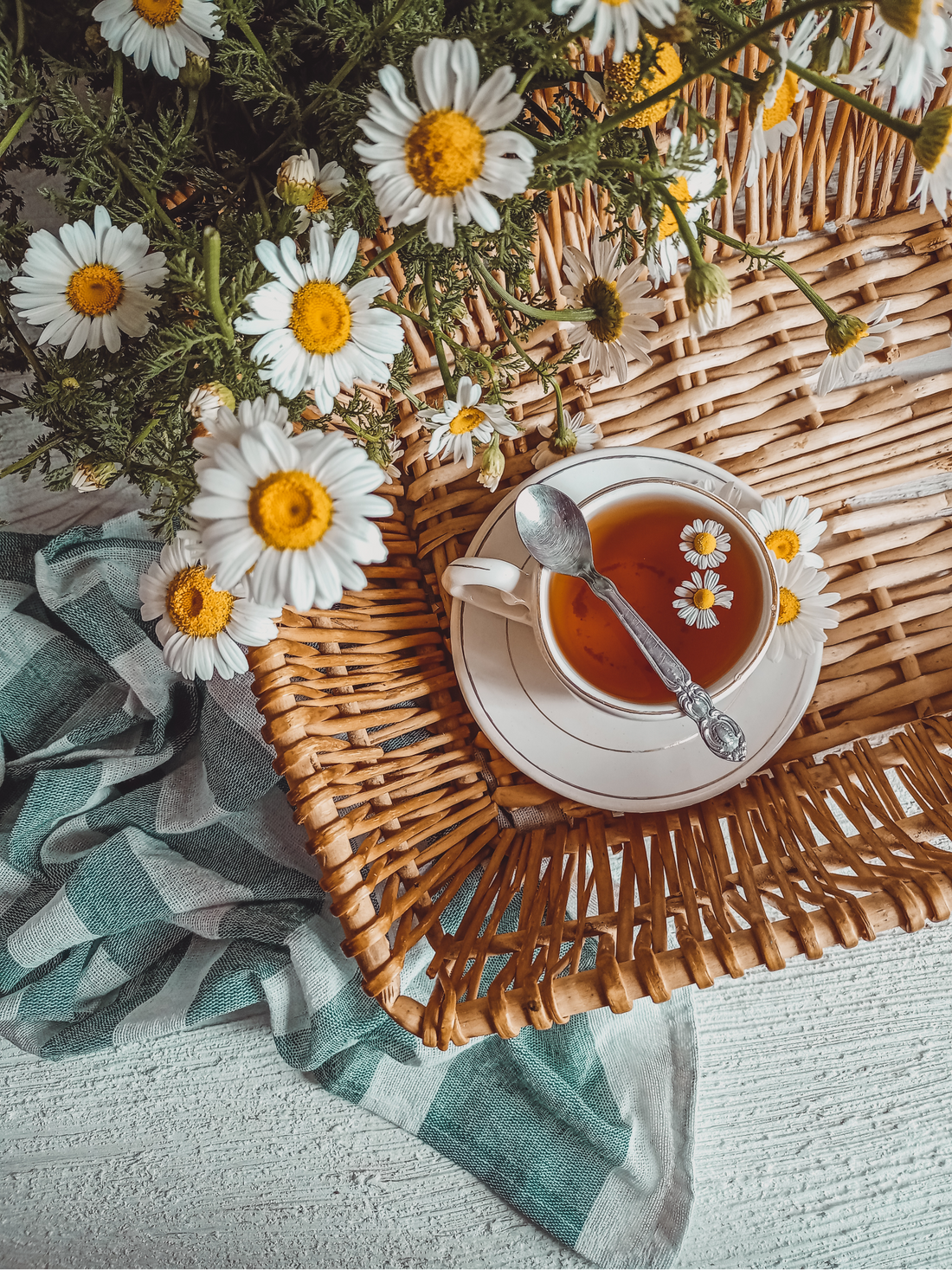 Herbal tea in a cup on a wicker basket with daisies